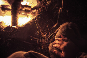 Man’s hand stroking his resting and sleeping pet dog friend in camping site nearby fireplace...