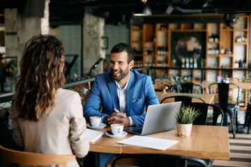 Happy businessman talks to female colleague during coffee break in cafe.