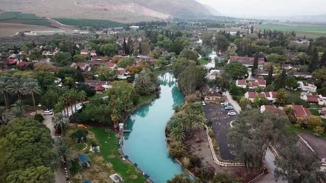 Aerial view flyover kibbutz Nir David, North of Israel. A view of farmland close to Beit shean valley with river channel dividing east and west side and Small Town With Red rooftops.