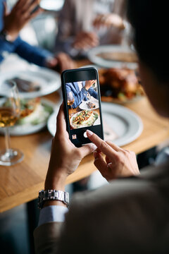 Close-up of businesswoman photographing food with smart phone while having lunch at restaurant.