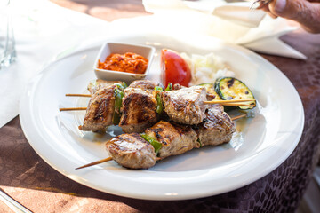 Barbecue skewers with juicy meat and sauce on plate, closeup. Grilled meat and vegetables.