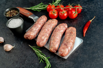 raw sausages for grilling, on a meat knife on a stone background