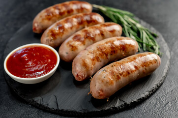 grilled sausages with spices, rosemary on a stone background