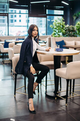 Beautiful young woman drinks coffee in cafe before important working meeting