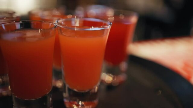 Pan up: Many red or orange shots at bar counter in pub
