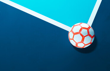 Close-up of a white futsal soccer ball laying on the line in the corner of a blue indoor soccer field