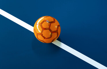 Orange futsal ball with light glow on the line of a blue indoor soccer field