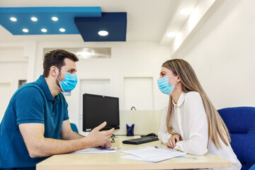 Obraz premium Paperwork for technical inspection and corona virus. A man and a woman are in a meeting in the office. The man explains something with his hands as she looks him straight in the eye