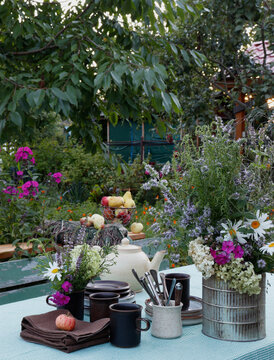 A table set for tea in the garden on a summer evening. On the table is a chocolate muffin and ceramic cups.