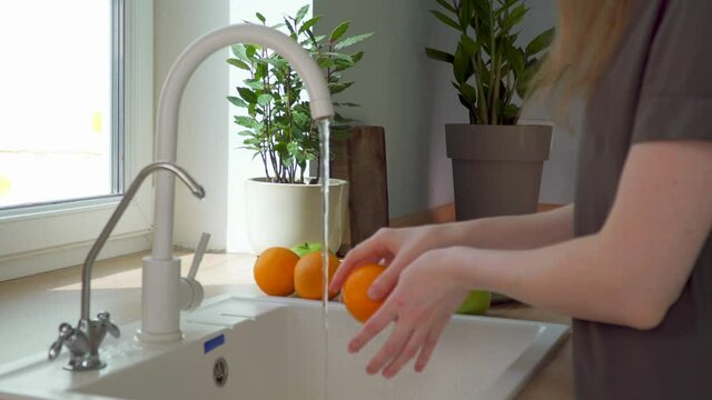 Food online delivery. woman washes groceries from store. Take fruit out of paper bag by kitchen sink. Healthy vegetarian breakfast. Delicious vitamins. purity of products. Happy woman fruit at kitchen