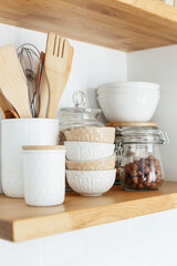 Kitchen shelves with various white ceramic and glass jars. Open shelves in the kitchen. Kitchen...