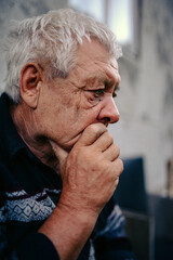 an elderly man looks thoughtfully into the distance