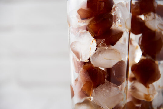 Coffee Ice In A Tall Glass With Straws On A White Wood Background. Cold Tasty Summer Refreshment Beverage Concept. Selective Focus, Copyspace.