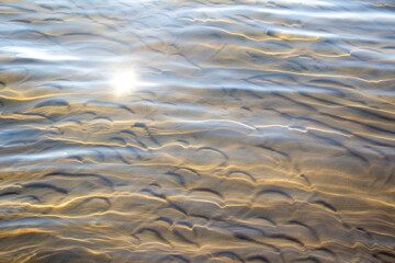 Sun glare on the water. The texture of the surface of a lake with a cave bottom.