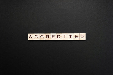 Word accredited made up of wooden blocks on black cardboard background. Minimum concept of accreditation. - obrazy, fototapety, plakaty