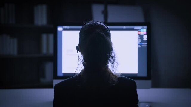 the back of the hacker call center working with computer at night
