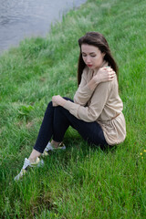 beautiful brunette woman sitting on green grass.