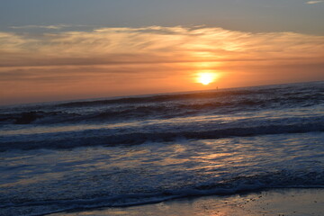Fototapeta na wymiar orange sun setting on the west coast horizon with a view of the ocean tide
