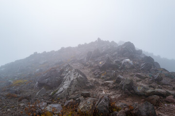 栃木県那須郡那須町の那須岳に霧の中で紅葉を見るために登山している風景 A view of climbing Mt. Nasu in Nasu-machi, Nasu-gun, Tochigi Prefecture, to see the autumn leaves in the fog.