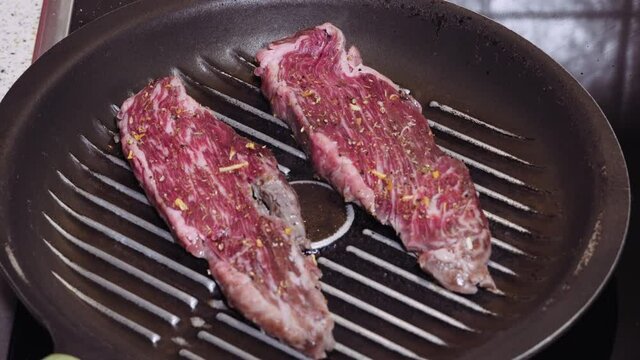 Raw wagyu meat gold label 9+ top view, cooking on a pan. Human flips steak premium cut flap variety with spices on hot fryer.