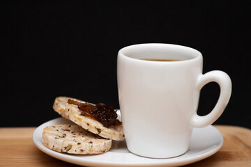  a cup of coffe beside a  rice vegan cookies with jelly on the top