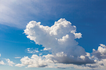 Heart shaped cloud on bright blue sky.