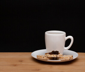 cup of coffe beside a rice vegan cookies with jelly on the top under the wood table