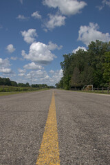 Worn out country road winding towards the horizon on a cloudy day 