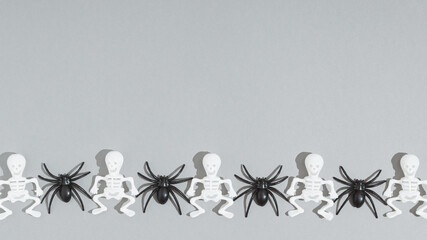 Halloween decorations on pastel gray background. Halloween minimal concept. Flat lay, copy space. Skeletons and spiders.
