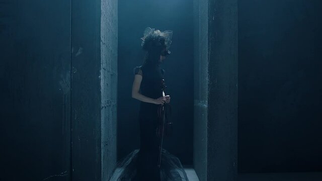 Black dressed young girl staying with the violin in mystic place . Alone female musician plays the violin . Mystical scene . Shot on ARRI ALEXA Cinema Camera in slow motion .
