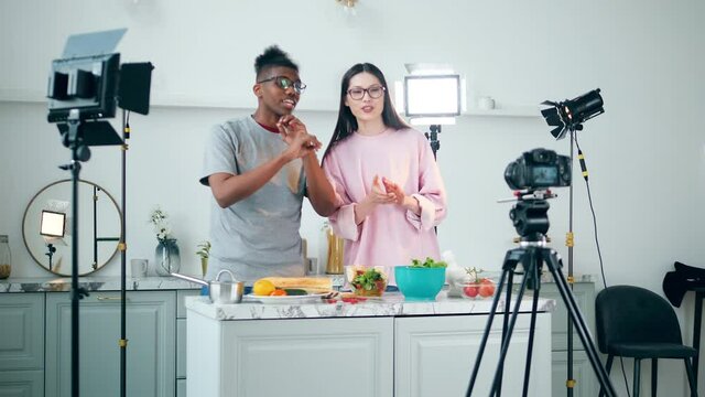 Cheerful young people are shooting a vlog in a studio kitchen
