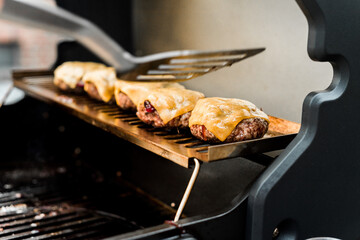 Rindfleisch Burger für Hamburger auf dem Grill mit Käse und Zwiebeln überbacken