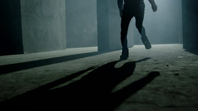 Evil clown , jester or joker running and jumping inside dark maze . Mystic video of buffoon in labyrinth . Fool or joker escape . Vision of horror dream . Shot on ARRI ALEXA Cinema Camera in slow .