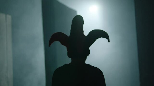 Evil clown , jester or joker running and jumping inside dark maze . Mystic video of buffoon in labyrinth . Fool or joker escape . Vision of horror dream . Shot on ARRI ALEXA Cinema Camera in slow .