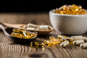 Close-up view of Andrographis paniculata( Kariyat )capsules with Golden capsules fish oil on spoon wooden, Supplement product, Alternative medicinal herb healing concept, and good healthy.