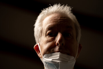 Photo of an old man incorrectly wearing his face mask not covering his nose and mouth