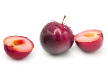 Ripe fresh organic plums whole and two half in water drops isolated on white background.