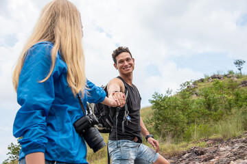 Handsome man carrying a hand bag to hold his girlfriend carrying a camera during a trekking trip