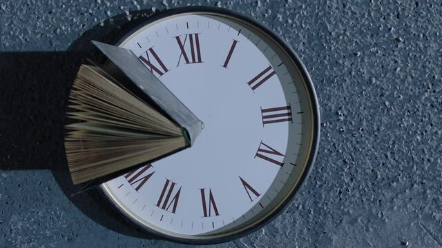 Book's pages turning by wind on 24 hours antique clock with classic roman numerals . Wind browse pages of old historic book . Mystical , abstract and symbolically video. Shot on ARRI Alexa camera .