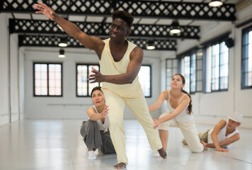 Obraz premium Positive afro american man studying movement of contemporary dance in classroom with his friends