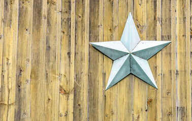 Light blue star on a background of vertical rustic yellow pine beadboard.  Copy space.