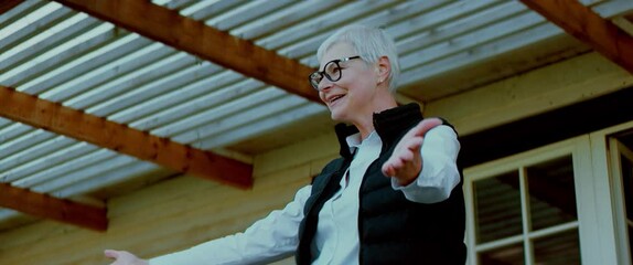 Portrait of happy smiling grandmother greeting and hugging grandchildren on a doorstep of her house. Shot with 2x anamorphic lens