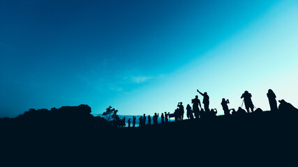 Naklejka na ściany i meble Silhouettes of tourist crowd waiting for the sunrise and doing activity, taking a photo, selfie with nature on the hill at viewpoint
