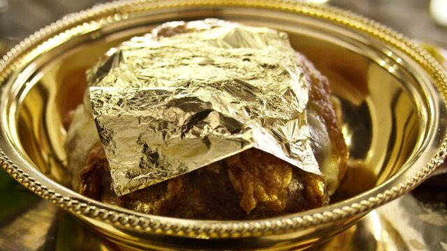 Chief cooker put 24 karat gold flake on meat dish . Eating food covered in gold . Delicacy expensive food with golden plate . Shot on RED EPIC Cinema Camera in slow motion .