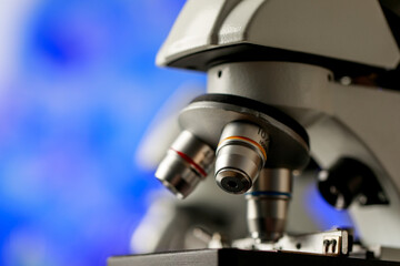 Closeup shot of microscope with selective lens objectives for various magnification or observation scales used as apparatus in microbiology lab for physical substance research and cell study.