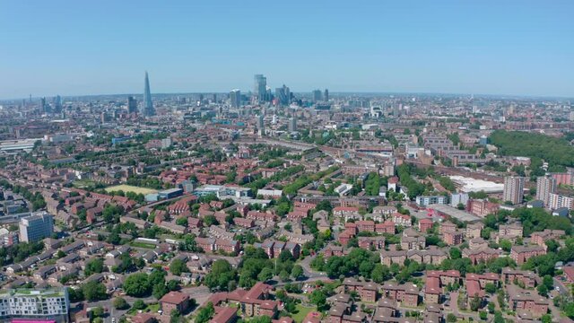 Dolly back drone shot of City of London skyscrapers from residential Southwark