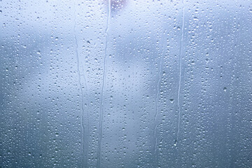 Raindrops on glass with blurred blue background