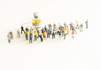 Group of people (figurine) standing against the Coronavirus COVID-19 vaccine and  syringe for injection .Coronavirus vaccine, population immunization campaign concept background.