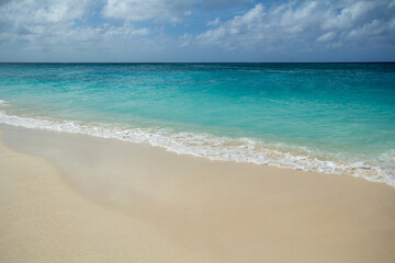Fototapeta na wymiar Soft foamy waves forming on a peaceful and relaxing sandy Beach in Grand Caymen. 