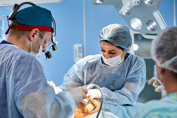 cosmetic liposuction surgery in actual operating room setting showing surgeons group during...